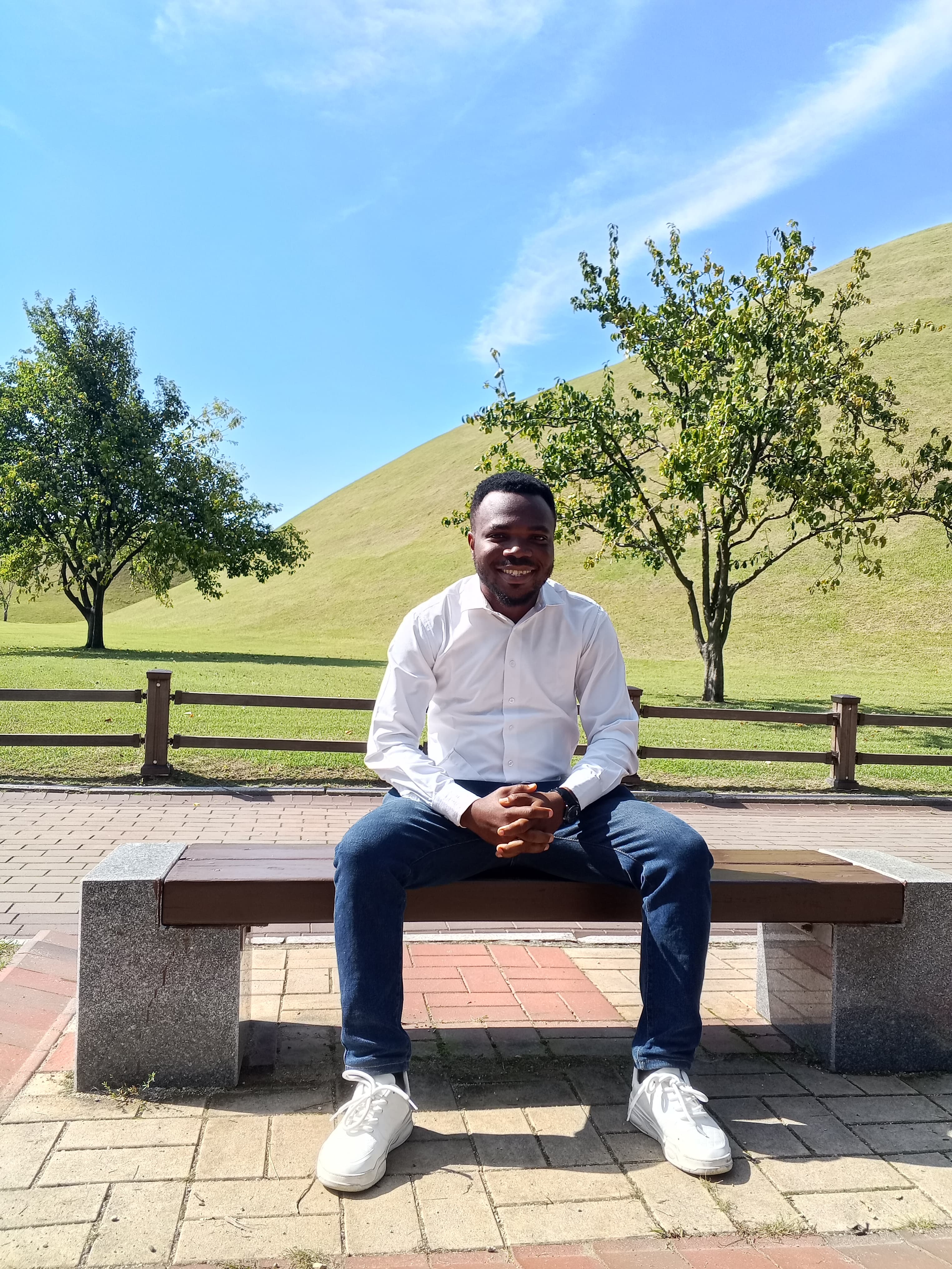 Anthony Uchenna Eneh sitting outdoors on a bench