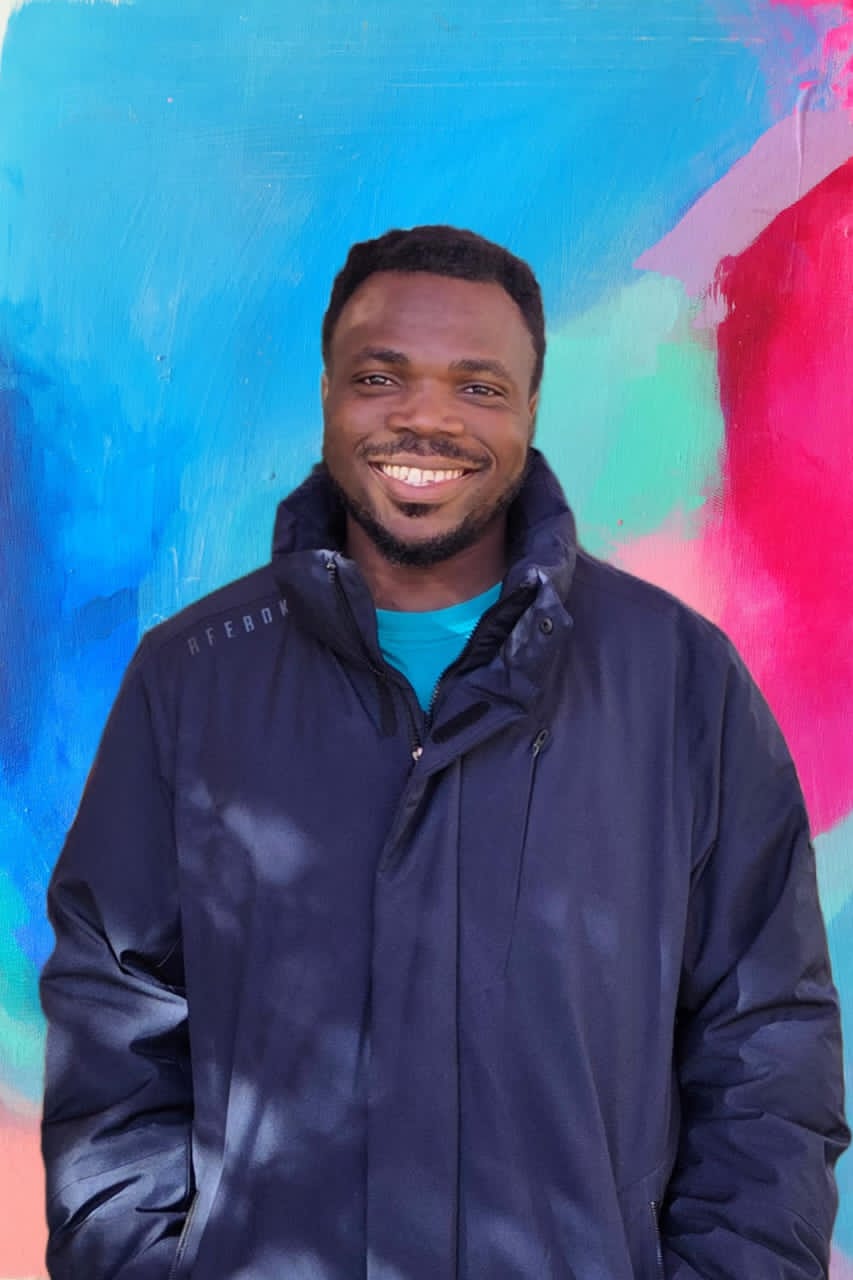 Anthony Uchenna Eneh smiling in front of a colorful wall
