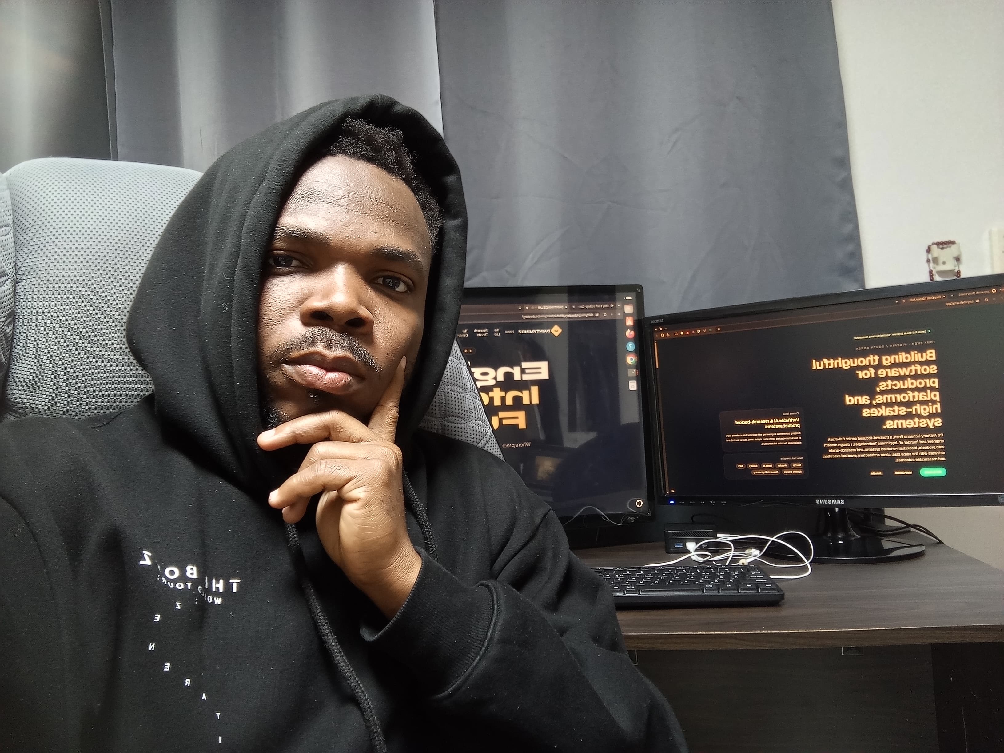 Anthony Uchenna Eneh working at a desk with dual monitors